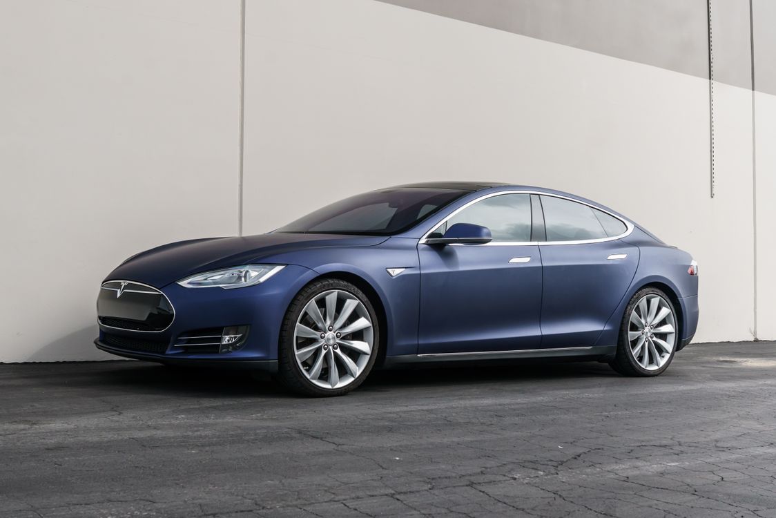 Dark blue Tesla Model S side profile against a concrete wall